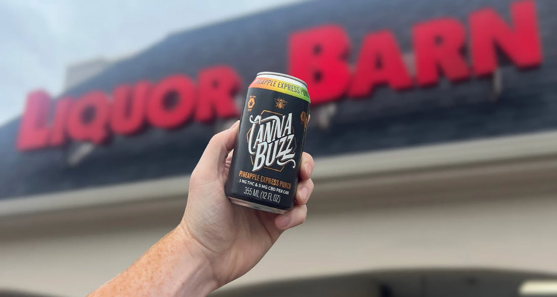 Man's hand holding up a Pineapple Express Punch can and a Liquor Barn is in the background